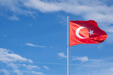 Turkish flag on a cloudy blue sky background.