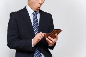 スマートフォンを操作するスーツ姿の男性　驚く　びっくり