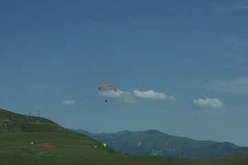Paraglider flying over mountains in summer day
