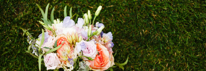 Bridal bouquet. The bride's bouquet. Bouquet of white, pink and green colors with silk ribbons of pastel color on grass background
