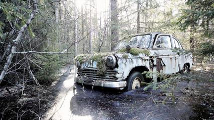 Old abandoned car stuck in frozen flood in the forest in Southern Finland. 