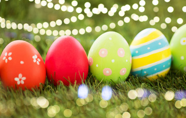 easter, holidays and tradition concept - row of colored eggs on artificial grass