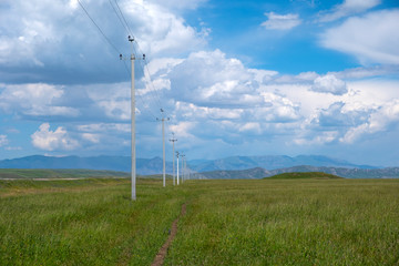 Fototapeta na wymiar Cable post green meadow. Green energy. Sky blue background.