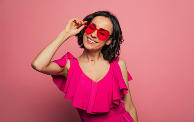 Females holidays. Beautiful trendy happy glamorous young woman in fashion wears and cool glasses in pink vivid style.