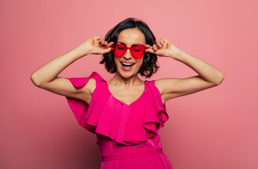 Females holidays. Beautiful trendy happy glamorous young woman in fashion wears and cool glasses in pink vivid style.