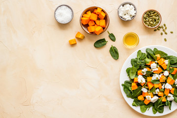 Fototapeta na wymiar Salad with pumpkin and basil - near ingredients - on beige background top-down copy space
