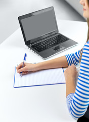 education, technology and people concept - student girl with exercise book, pen and laptop computer