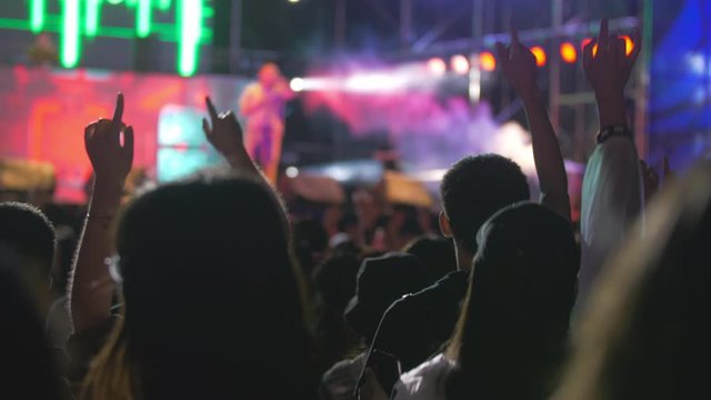 people watch band performing on the stage on music festival young people waving hands enjoy the rap music live show