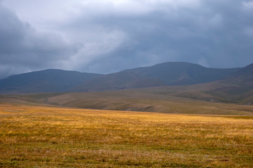 Scenic mountain valley landscape with rain clouds background. Nature background. Rural scenery. Dramatic scene. Autumn background. Mountain valley. Assy plateau in Kazakhstan.