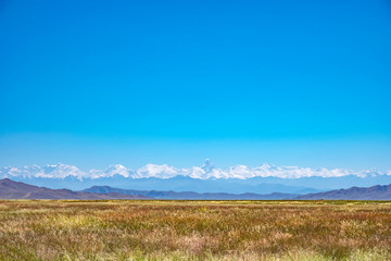 Fototapeta premium Mountain range landscape with meadow. Sunset view. Amazing natural background. Mountain hiking. Khan Tengri peak.