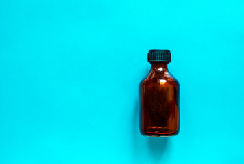 Glass bottle for medicine on blue background.  Brown bottle for liquids.