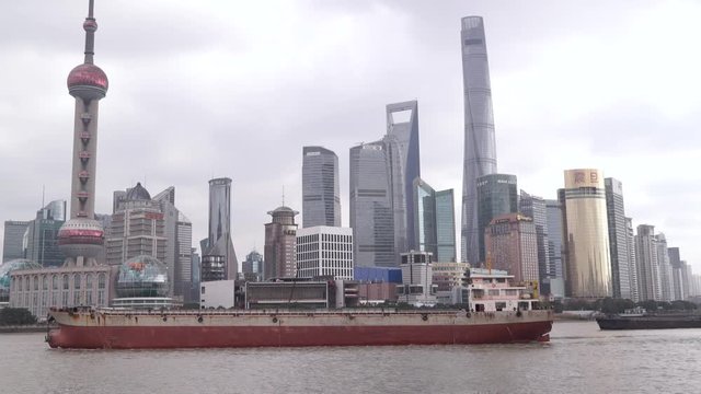 Shanghai The Bund or Waitan urban cityscape skyline. Cargo ship sails near skyscrapers