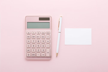 Rose gold calculator with pen and business card on pink background, flat lay