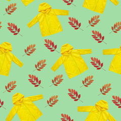Yellow raincoat, dry autumn leaves on neo mint background seamless pattern. Trendy fashion color, outwear style clothes flat lay texture. Hello Fall rainy day concept. Bright kids outdoor rain jacket.