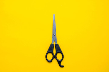 Black scissors on a yellow background. Top view. Copy, empty space for text