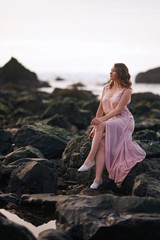 Girl in evening dress at sunset on the ocean, Oregon. Cannon Beach. Femininity