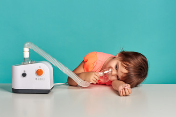 Cute little girl playing with nebulizer and teddy bear. Studio shoot. Allergy concept