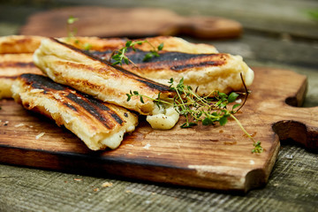 Grilled cheese puff pastry on the wooden cutting board. Snack, baking.