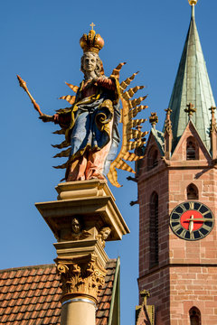 Marienfigur mit Krone und Zepter steht in Ladenburg auf einer S&auml;ule vor der Kirche