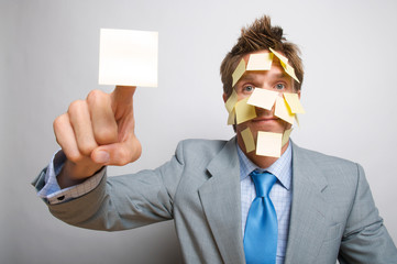 Overworked office worker covered in yellow sticky notes pointing at copy space reminders