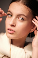 A close-up portrait of a beautiful young girl with brown hair and green eyes with natural makeup in light clothing