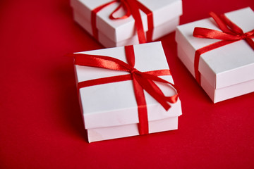Luxury white gift boxes with red ribbon on red background.