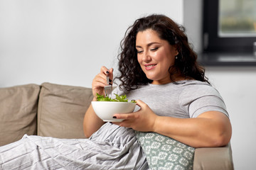 food, diet and people concept - happy smiling young woman eating vegetable salad at home