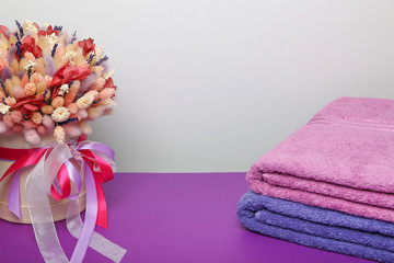 folded towels and dry flower composition on purple table 