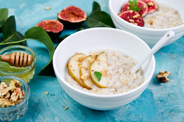 A bowl of porridge with pears slices and walnuts.