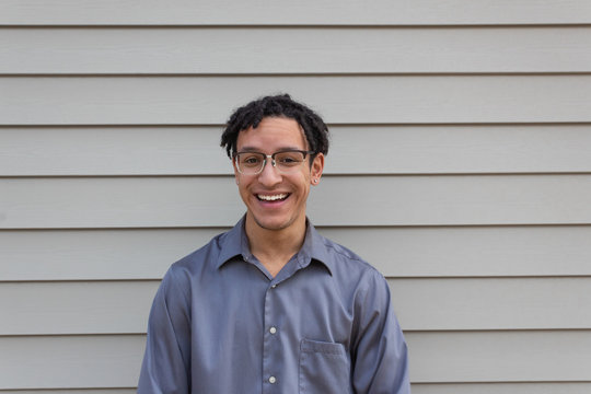 Laughing young millennial man, handsome mixed race male with natural hair twists,  horizontal aspect