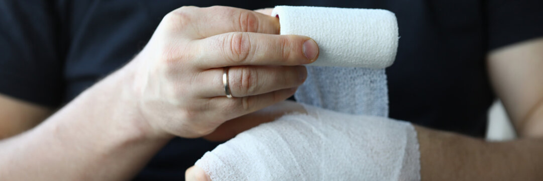 Male hand with tight elastic bandage on arm closeup. Self help sprain concept