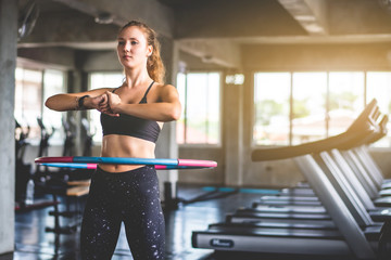Beautiful young caucasian woman doing hula hoop during an exercise class at sport gym.  Healthy sports lifestyle, Fitness, Healthy and workout concept.