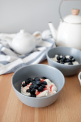 Tasty breakfast of Tvorog, farmers cheese, curd cheese or cottage cheese and blueberries in gray bowls. 
