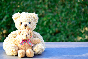 Cute teddy bear are sitting together on blurred grey table and sun reflection over nature background good feeling for couple, romantic symbol for your pattern design or your surprise valentine concept