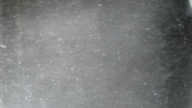 White particles swirling in a glass of water