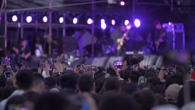 people watch band performing on the stage using mobile phone recording during strawberry music festival in Chengdu China 2019 young people waving hand enjoy the music live show
