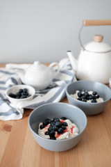 Tasty breakfast of Tvorog, farmers cheese, curd cheese or cottage cheese and blueberries in gray bowls. 
