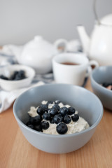 Tasty breakfast of Tvorog, farmers cheese, curd cheese or cottage cheese and blueberries in gray bowls. 