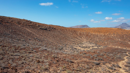 Fototapeta na wymiar Elevated views of the arid volcanic landscape surrounding the summit of Montana Amarilla towards Pico del Teide and the small terraced villages, in Costa del Silencio, Tenerife, Canary Islands, Spain