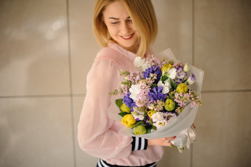 Smiling woman holding a beautiful flower bouquet of different fresh flowers.