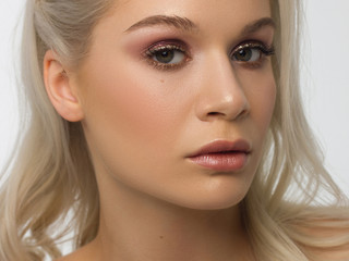 Fototapeta premium Close-up portrait of the cleanliness face of a beautiful woman with dark maroo smoky eyes makeup, natural full lips. Sexy model with clean shiny skin, clean face, long curly hair. glamorous image