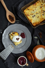 Cottage cheese casserole with raisins on a gray plate, poured sour cream on top. Flat lay, view from above. 