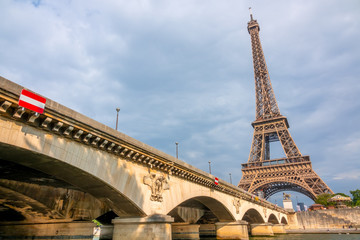 Fototapeta na wymiar Eiffel Tower in Cloudy Weather and Iena Bridge in the Sun