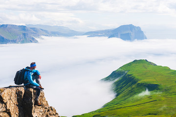Fototapeta na wymiar Hiker sitting on cliff, Mykines, Faroe Islands