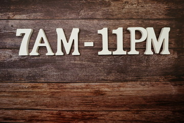 Opening Times 7 am to 11 pm letter on wooden background