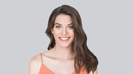 Beautiful young woman portrait. Smiling girl looking to camera. Isolated on gray background,...