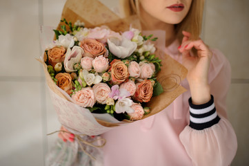 Woman holding blossoming bouquet in pastel colors in her hands.