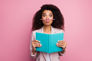 Photo of funny foolish dark skin student lady hold journal book not reading playing pen make fake mustache wear checkered blazer isolated pastel pink color background