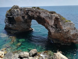 Rock arch isolated in the sea next to the coast.
