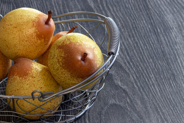 Poires Rocha, variété portugaise, dans une corbeille métallique sur fond noir